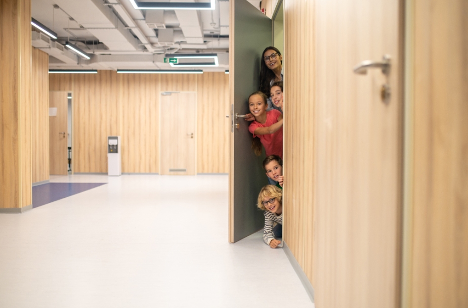 учитель и школьники выглядывают из приоткрытой двери в коридор