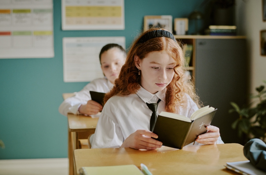 Школьница читает книгу за партой