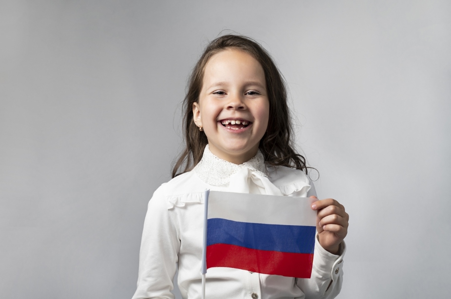 девочка в белой рубашке держит флаг РФ
