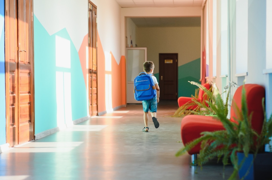 ученик с портфелем бежит по коридору школы